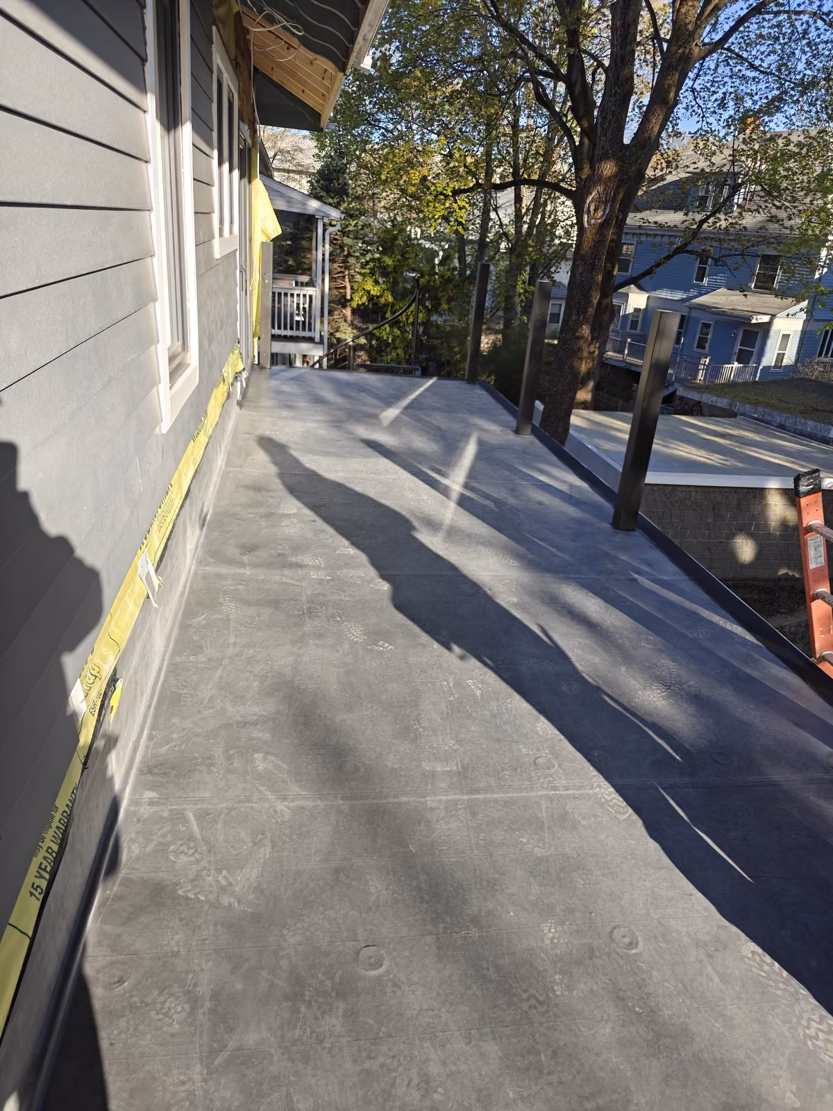 Finished flat rubber membrane roof beside gray siding