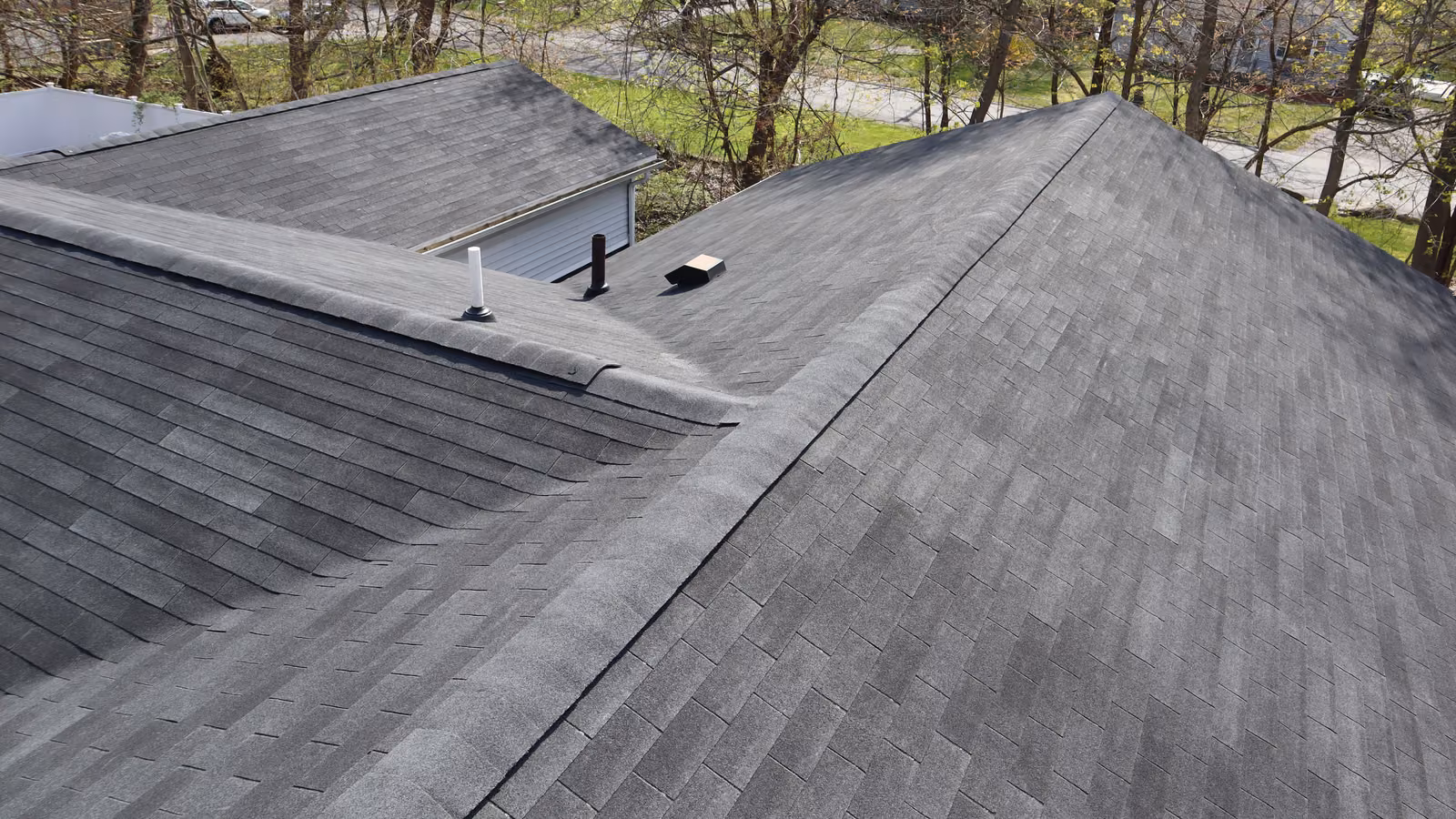 Aerial detail of a charcoal hip roof valley with rooftop plumbing vents