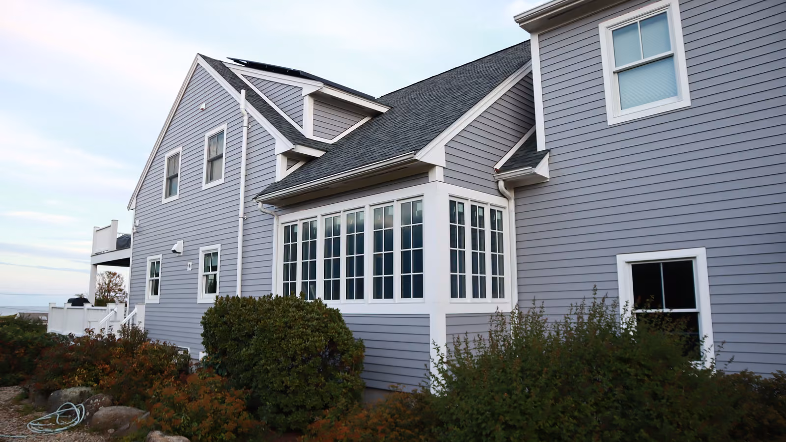 Side view of a Rockport home with a sunroom bay and new gray siding
