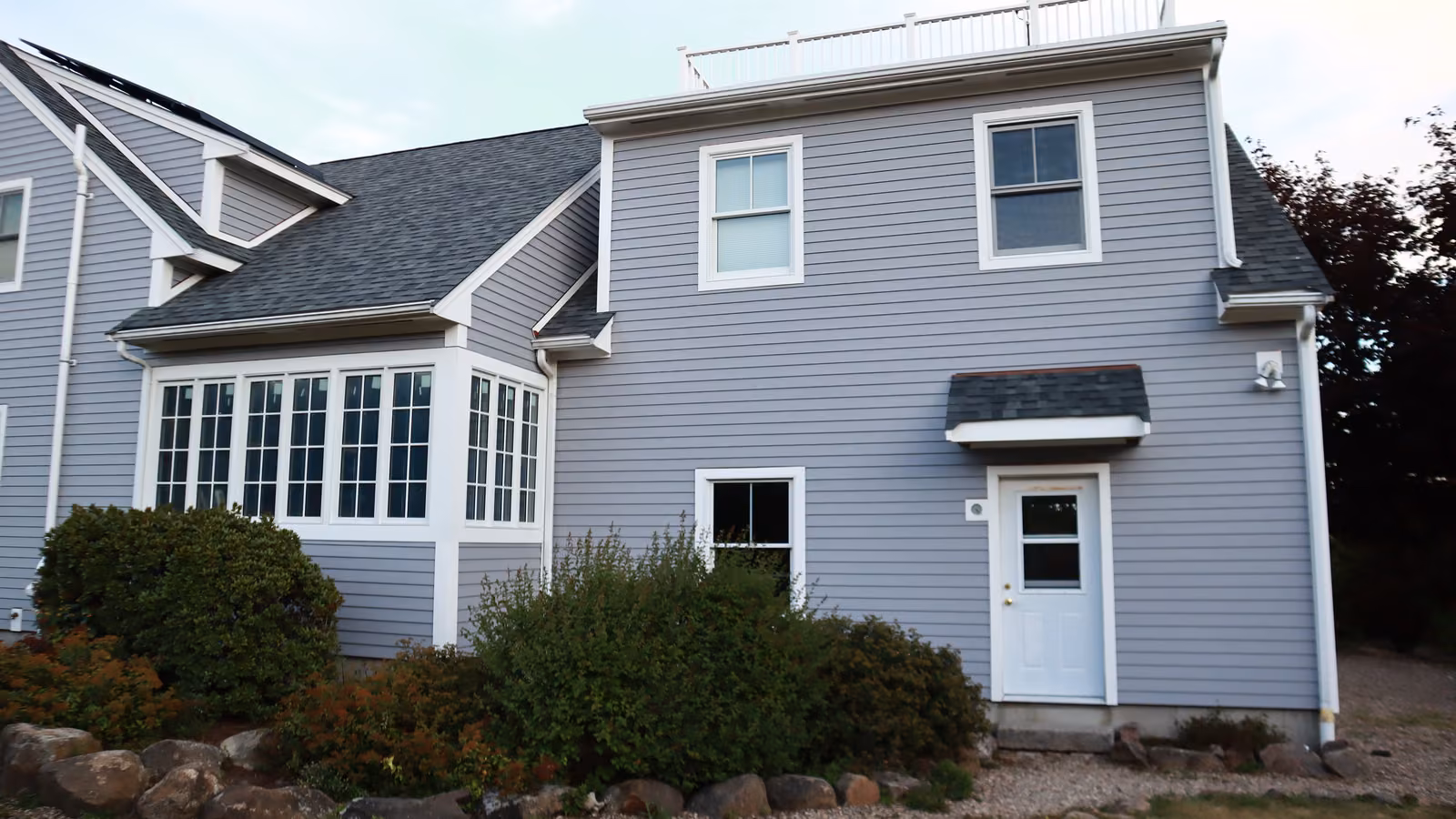 Front entry of a Rockport home with new gray lap siding and bay windows