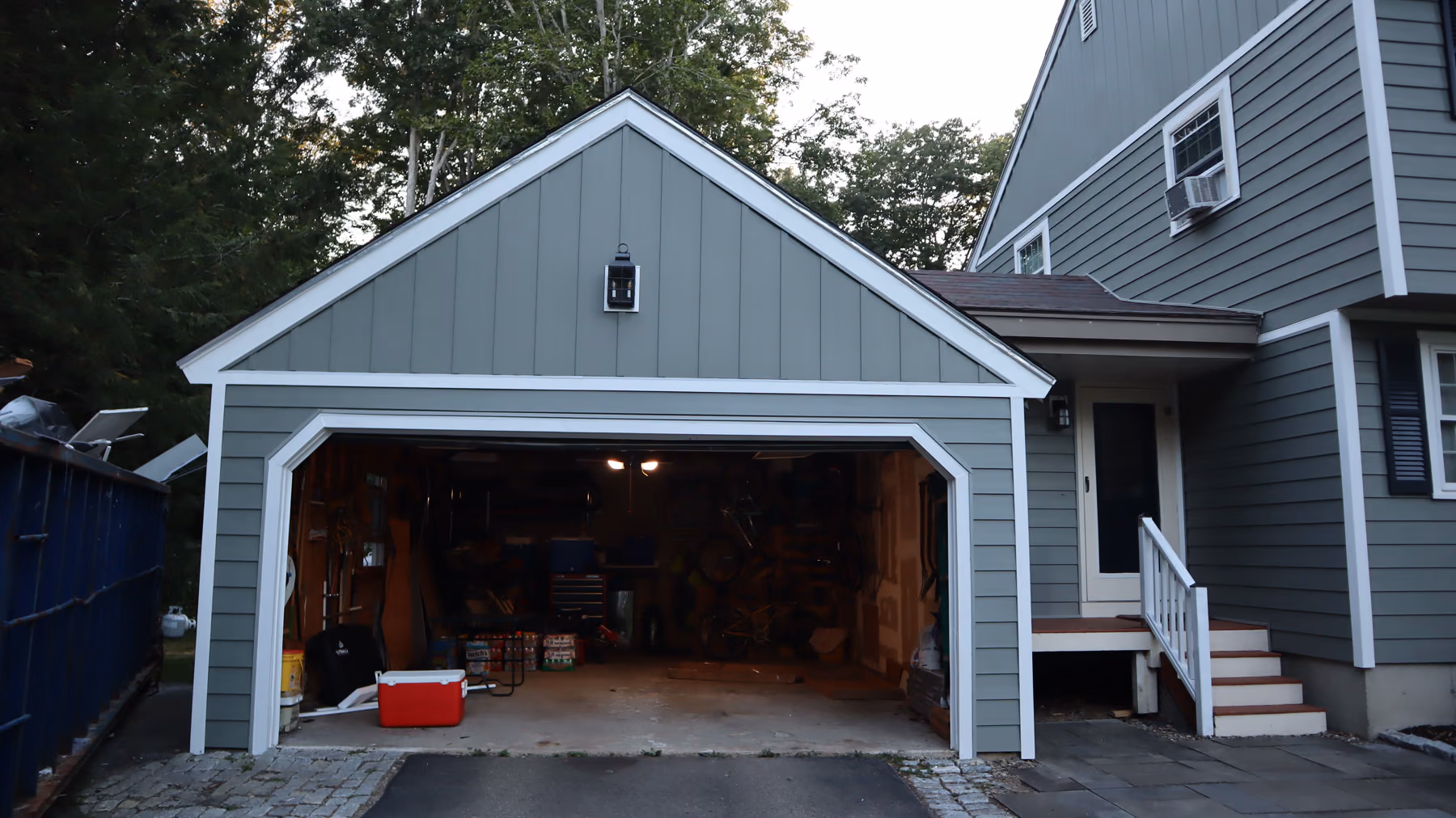 Head-on view of the attached garage with new green siding, white trim and matching board-and-batten peak