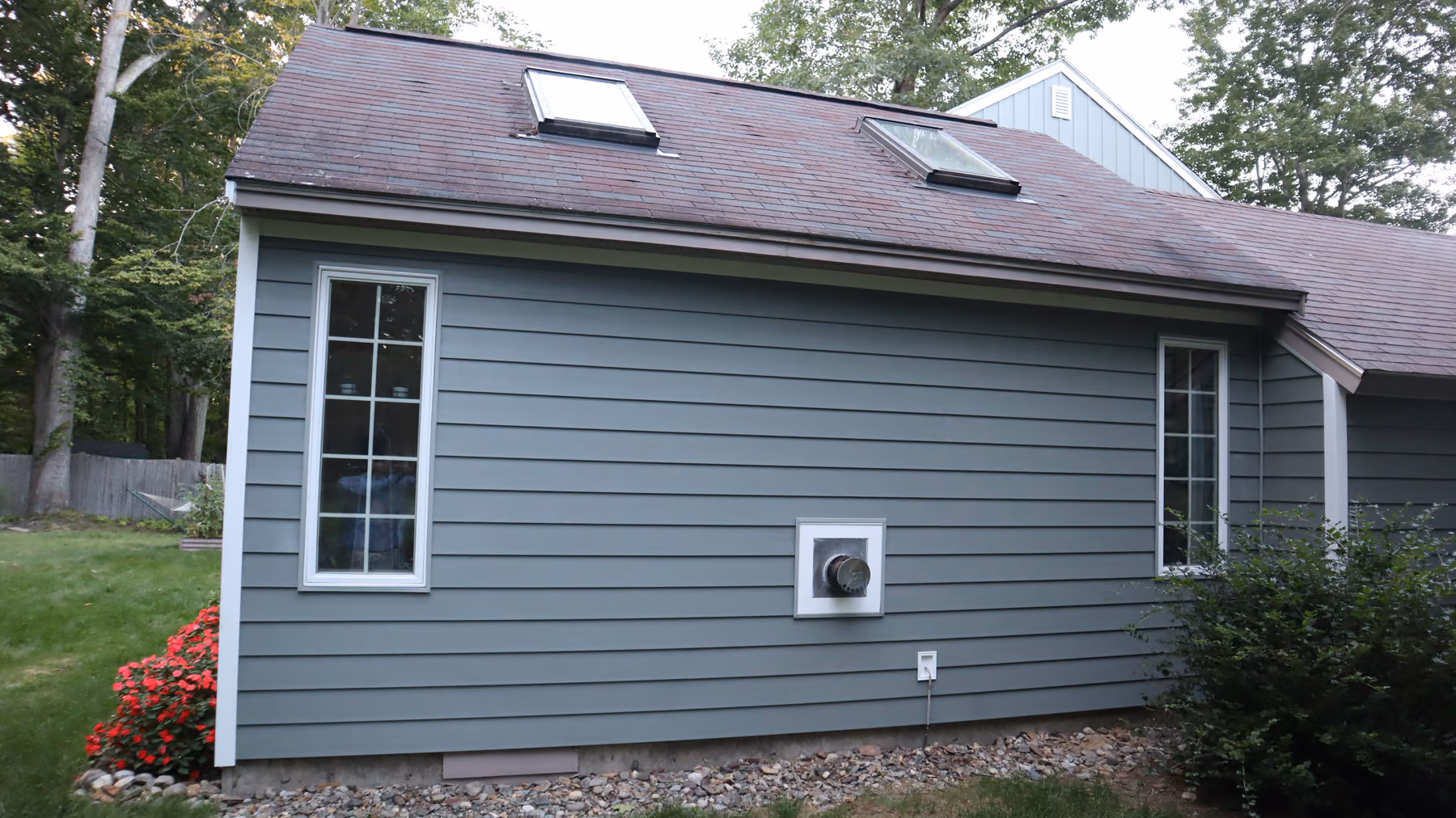 Rear addition with a sunroom bay in fresh green siding, white trim and a Palladian gable window